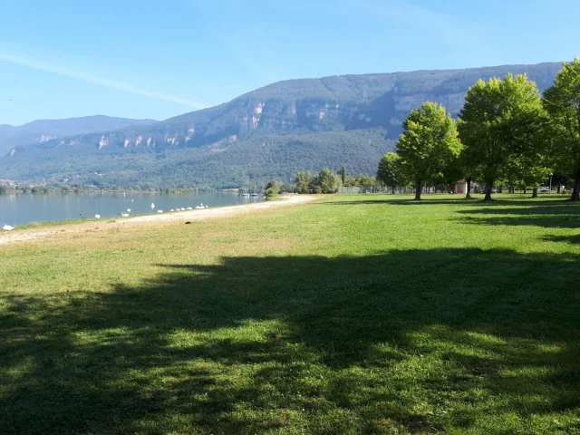 plage bordé par une pelouse avec des montagnes au loin